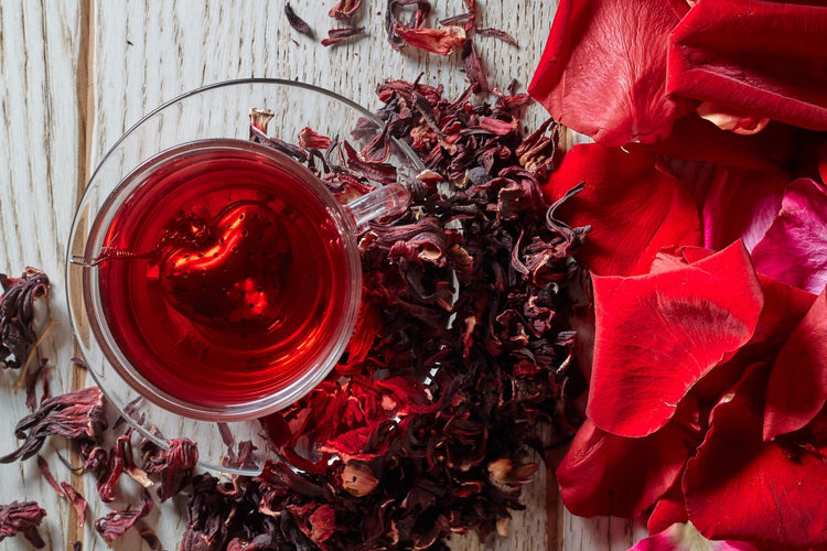 Red flowers with red tea in clear glass cup