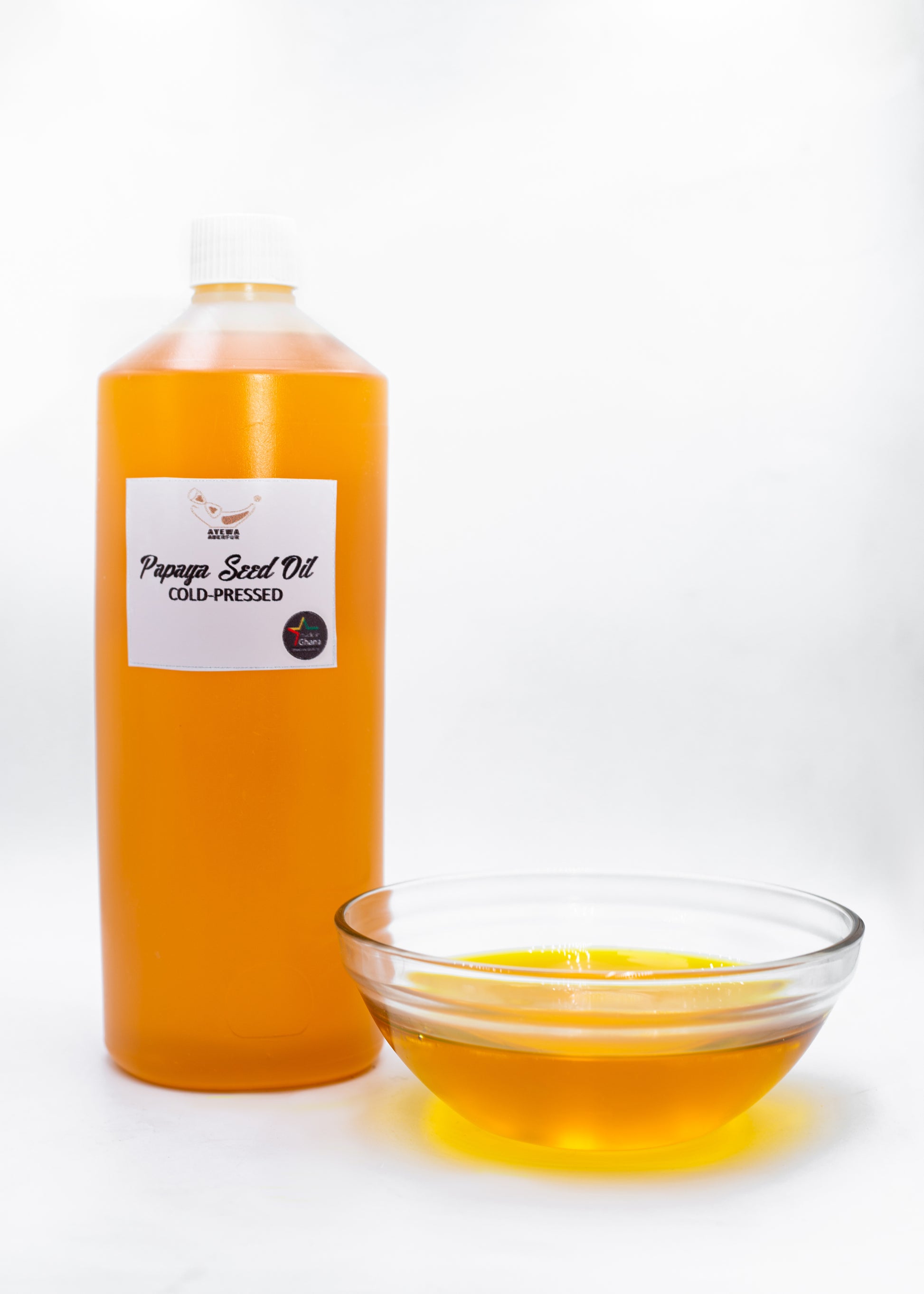 Bottle and bowl of papaya seed oil on a white background